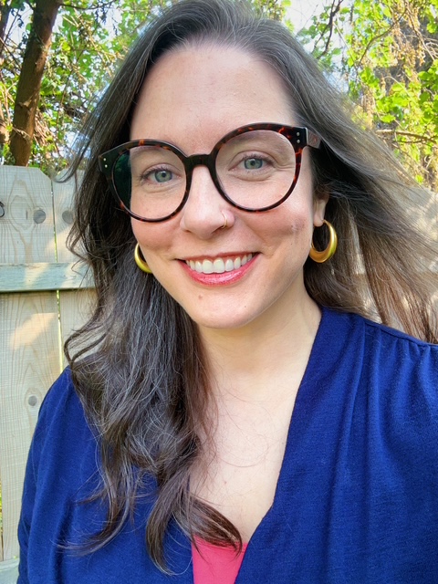 A light-colored desk with a notebook in the center, open to white pages, with colorful tabs holding down the pages, and a ...